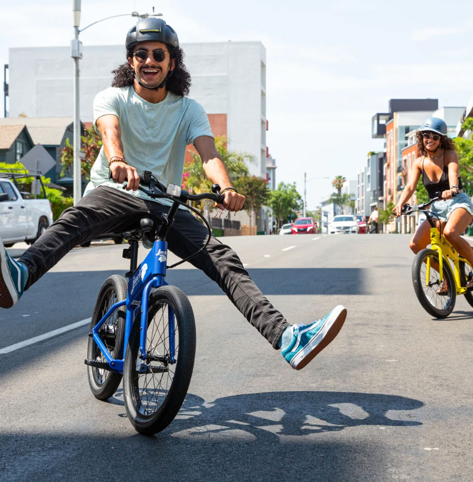 Two people riding electric bikes on a city street.