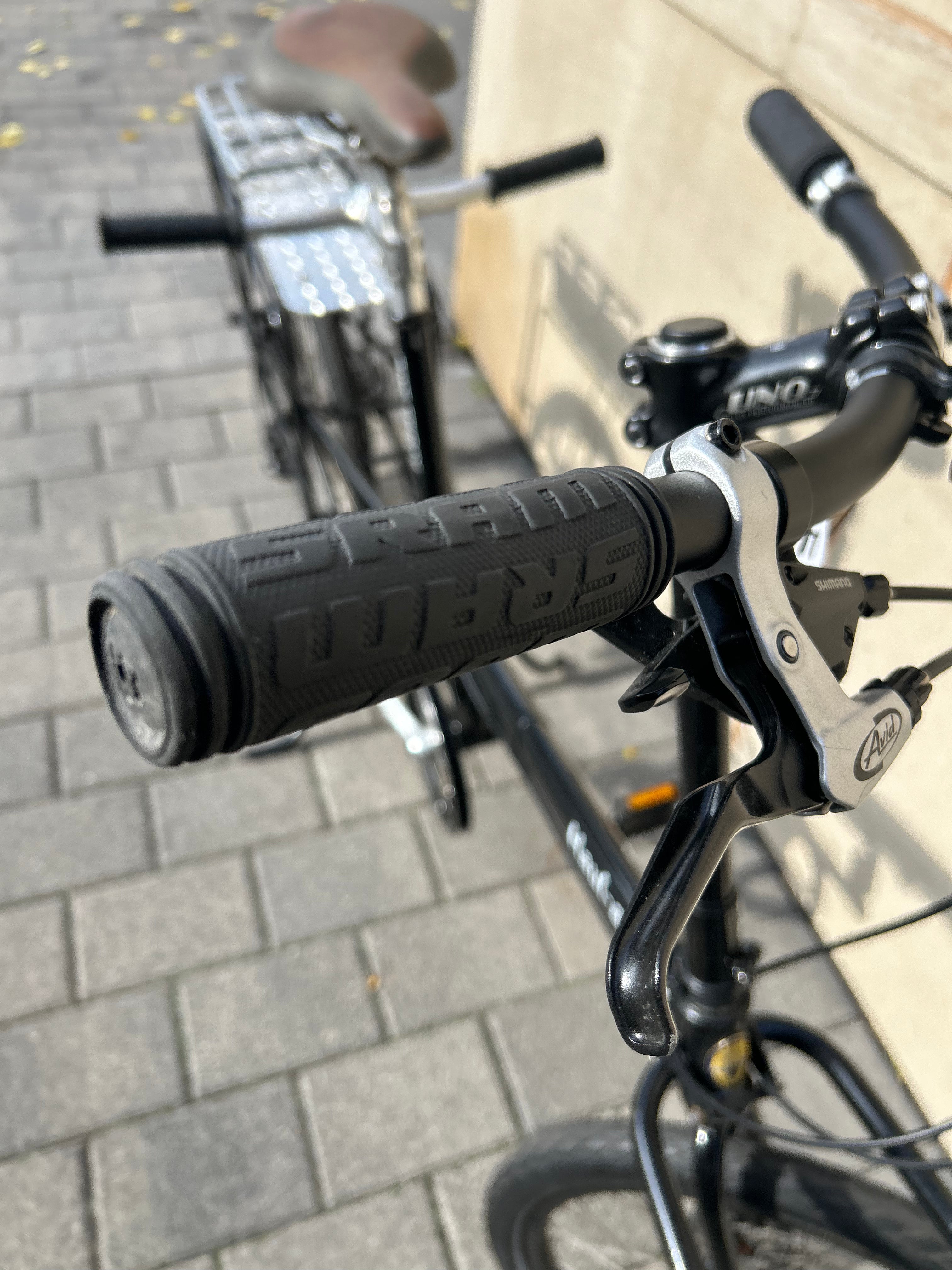 Close-up of a bicycle handlebar with black grips and brake lever on a paved surface.