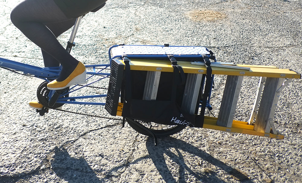 Person using a manual bike with a cart attached on an asphalt surface