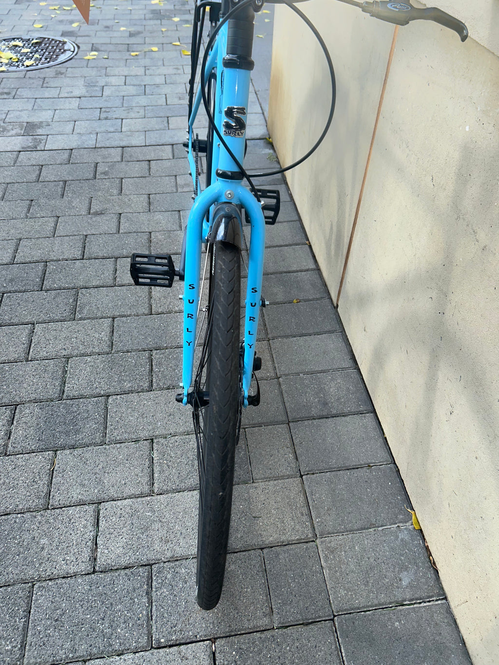 Blue bicycle leaning against a wall on a paved sidewalk