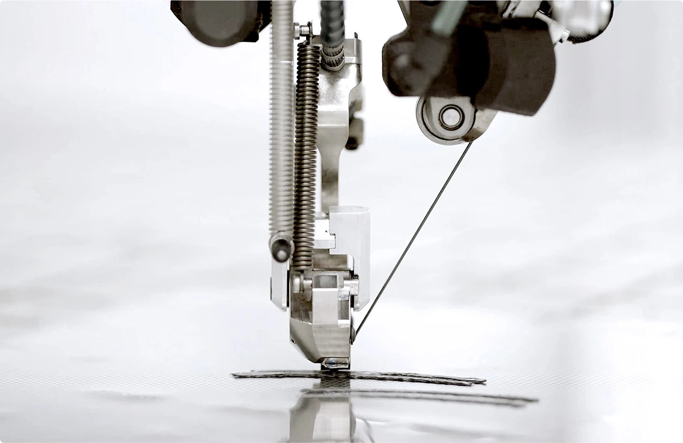 Close-up of a sewing machine needle and thread on a white background