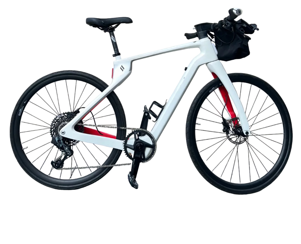 White bicycle with black seat and tires parked on a sidewalk next to a building with a Christmas wreath.