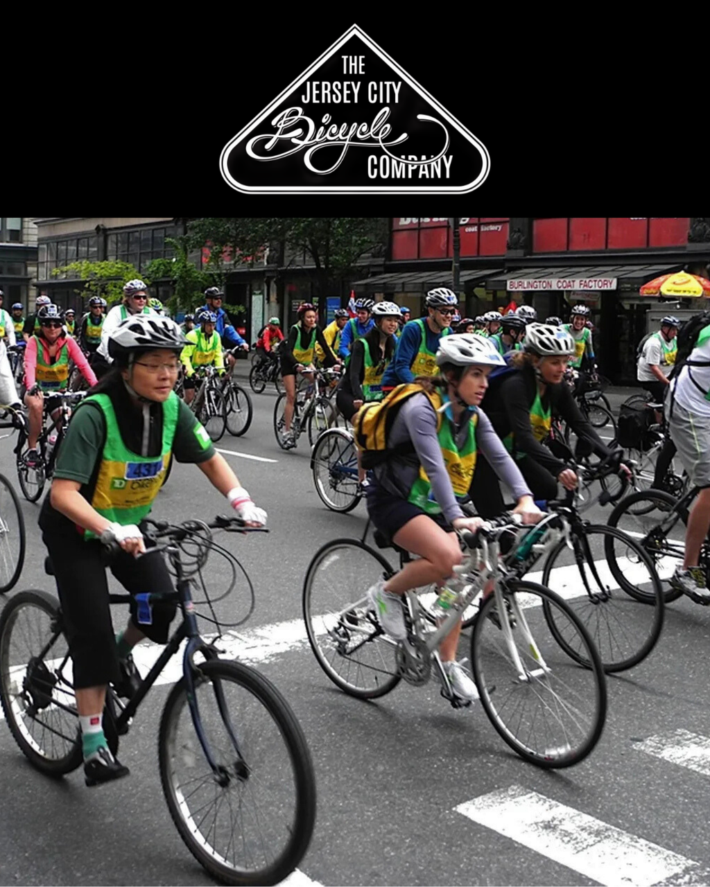 Group of cyclists on a street with 'The Jersey City Bicycle Company' logo above.
