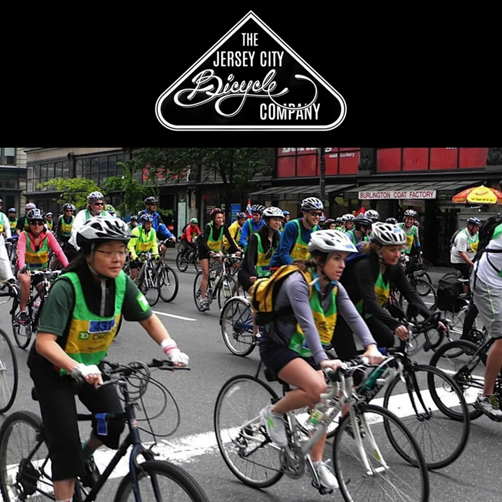Group of cyclists on a street with 'The Jersey City Bicycle Company' logo above.