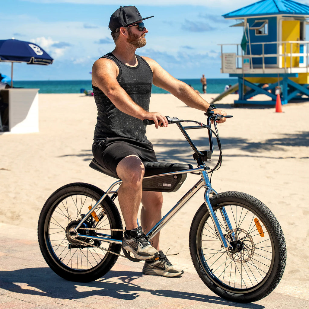 Man riding a bicycle on a beach with a lifeguard tower in the background