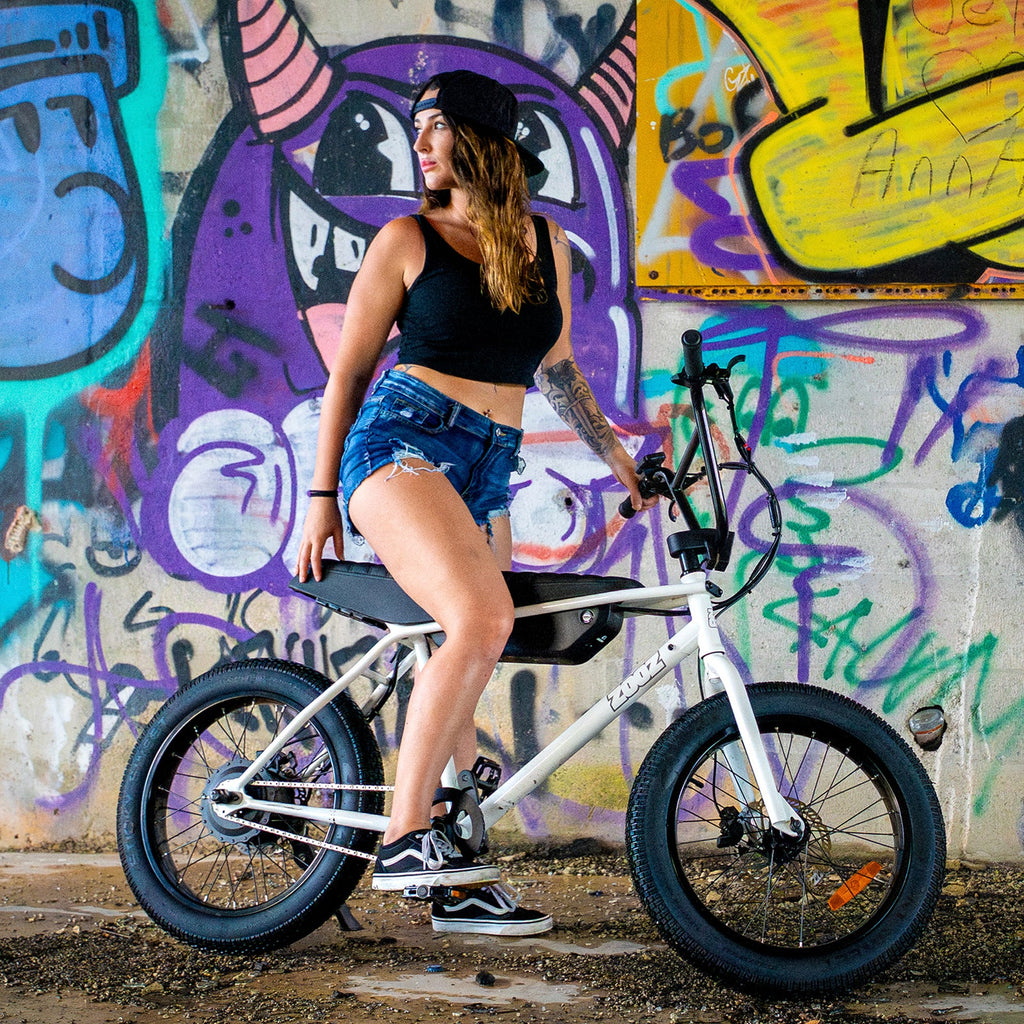 Woman with a white bicycle in front of a colorful graffiti wall