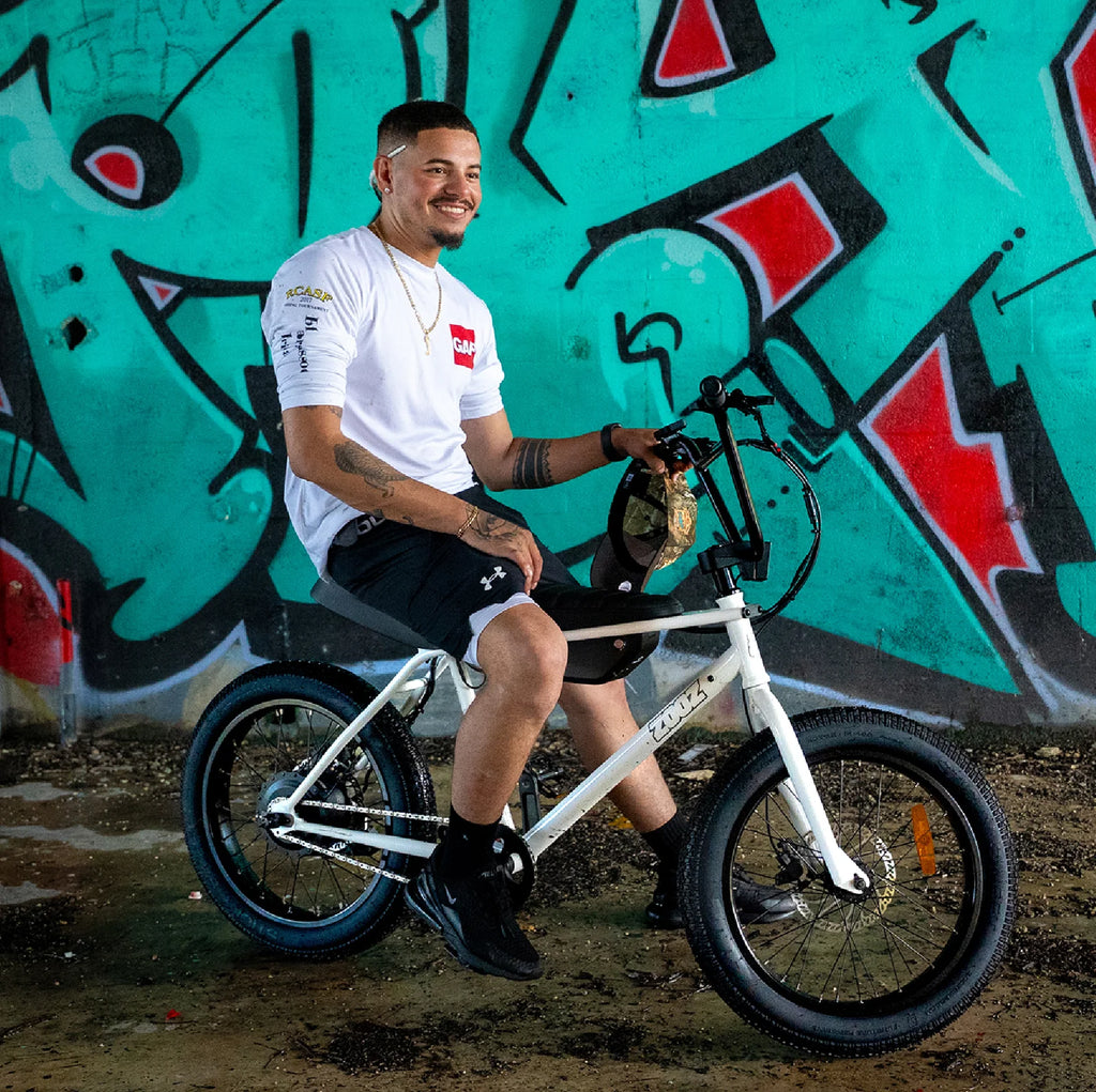Man sitting on a bicycle in front of a graffiti-covered wall